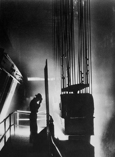Ford Motor Company foreman shields his eyes against fiery light of open hearth mill, Detroit, MI, 1929