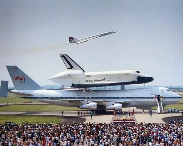 June 1983, featuring the Space Shuttle Enterprise mounted atop NASA's Boeing 747 Shuttle Carrier Aircraft, while a British Airways Concorde takes off in the background