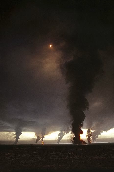 The sabotaged Ahmadi oil fields darken the Earth below, with the sun barely peaking through the dense black smoke Gulf War, 1991